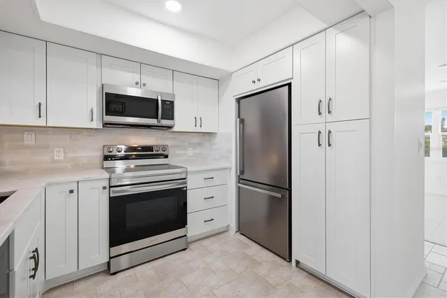 a kitchen with stainless steel appliances white cabinets white stove a microwave and a refrigerator