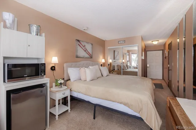 a spacious bedroom with a bed a fireplace and a chair