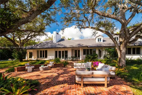 a dining room with furniture a large window and potted plants