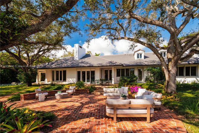 a dining room with furniture a large window and potted plants