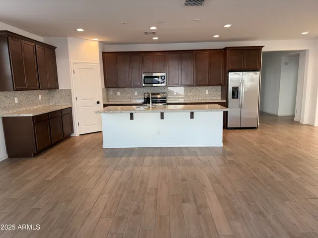 a kitchen with stainless steel appliances granite countertop a sink a microwave counter space and wooden floor