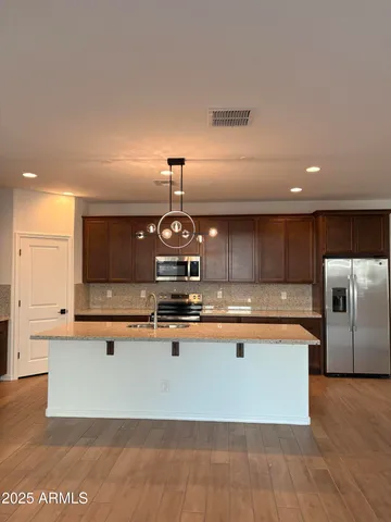 a large kitchen with stainless steel appliances a large counter top a stove and a refrigerator