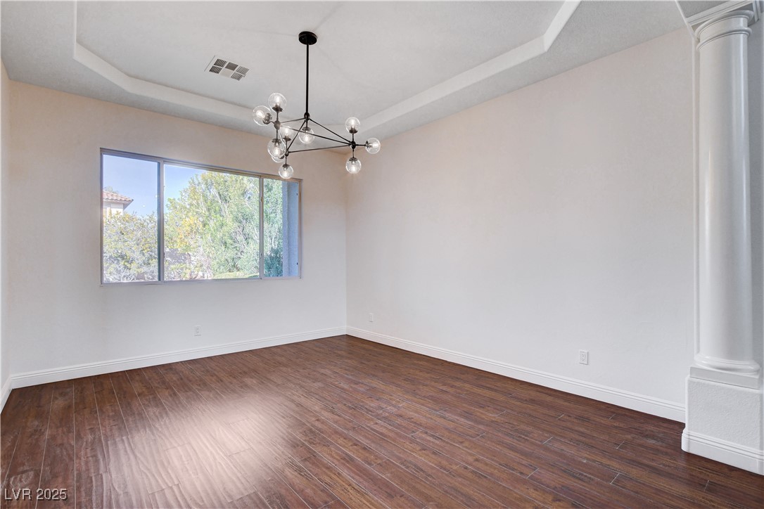 5148 Villa Vecchio Court Las Vegas, NV 89141 - Photo 13 of 71 Spare room with a tray ceiling, baseboards, dark wood-type flooring, and visible vents