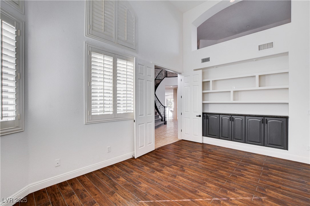 5148 Villa Vecchio Court Las Vegas, NV 89141 - Photo 17 of 71 Unfurnished room with visible vents, dark wood-type flooring, baseboards, stairway, and a high ceiling