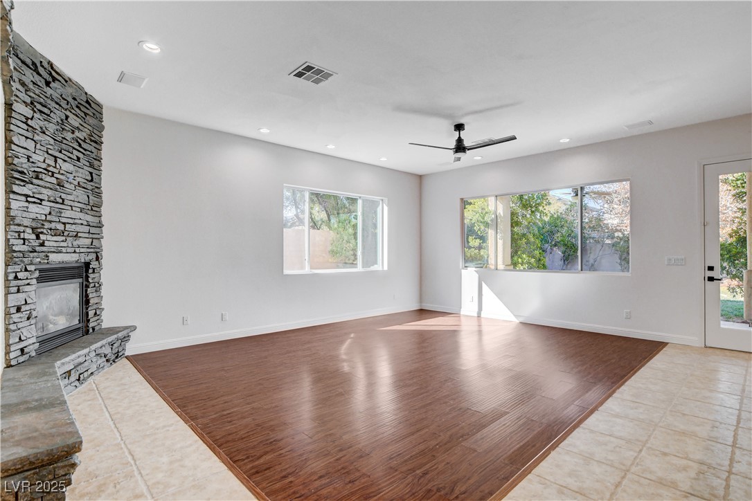 5148 Villa Vecchio Court Las Vegas, NV 89141 - Photo 20 of 71 Unfurnished living room featuring visible vents, baseboards, a stone fireplace, and ceiling fan