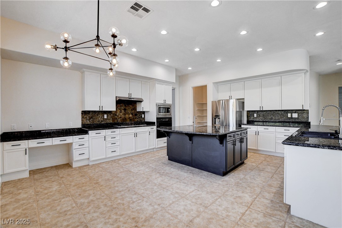5148 Villa Vecchio Court Las Vegas, NV 89141 - Photo 24 of 71 Kitchen with visible vents, under cabinet range hood, dark stone counters, appliances with stainless steel finishes, and a sink