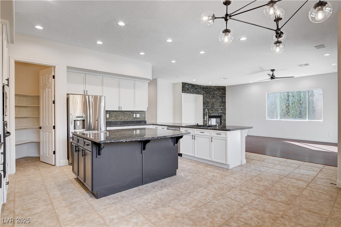 5148 Villa Vecchio Court Las Vegas, NV 89141 - Photo 71 of 71 Kitchen featuring a sink, open floor plan, a peninsula, white cabinets, and stainless steel fridge with ice dispenser