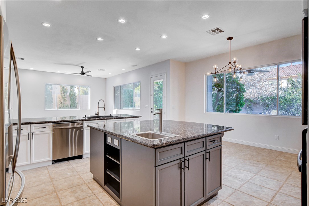 5148 Villa Vecchio Court Las Vegas, NV 89141 - Photo 25 of 71 Kitchen with dark stone countertops, visible vents, a kitchen island with sink, a sink, and appliances with stainless steel finishes