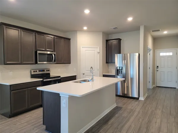 a kitchen with stainless steel appliances granite countertop a refrigerator stove a sink and dishwasher with wooden floor