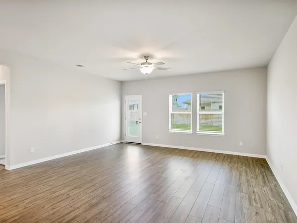 an empty room with wooden floor and windows