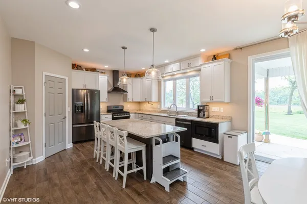 a kitchen with stainless steel appliances a dining table chairs stove refrigerator and cabinets