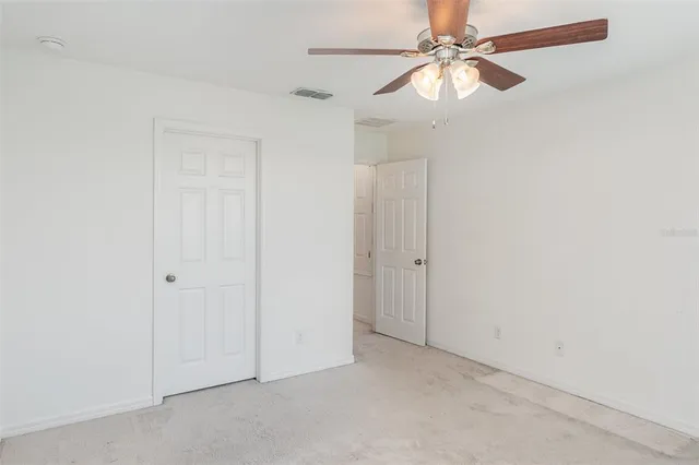 an empty room with a fan & a ceiling fan