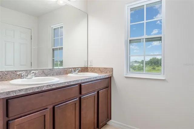 a bathroom with a granite countertop sink and a window