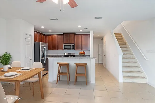 a kitchen with stainless steel appliances kitchen island granite countertop a refrigerator a stove a sink dishwasher and a dining table with wooden floor