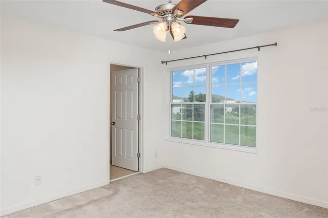 an empty room with a window and ceiling fan