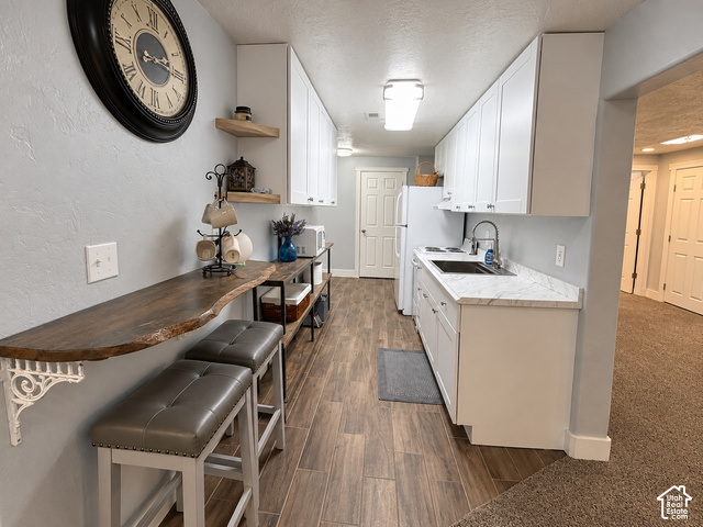1750 West 4100 North Helper, UT 84526 - Photo 40 of 50 Galley-style kitchen featuring wood-finish flooring, white cabinetry, a dark sink with a gooseneck faucet, and light-toned countertops