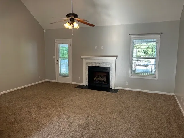 an empty room with chandelier fan and windows