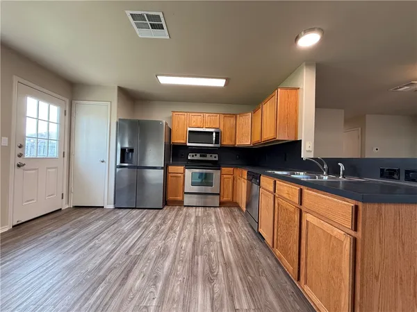 a large kitchen with granite countertop a large counter top stainless steel appliances a sink and cabinets