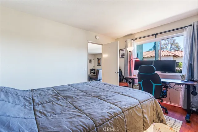 a bedroom with a bed table chair and a window