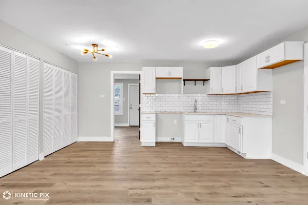 a large kitchen with cabinets wooden floor and a window
