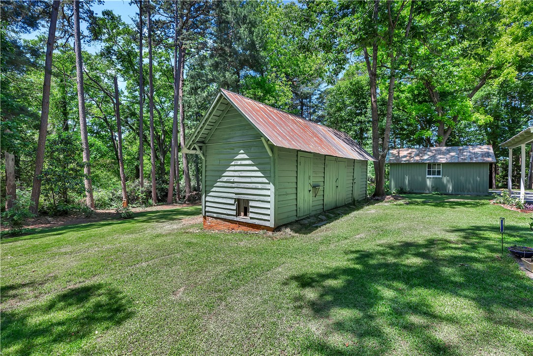 205 West Mauldin Street Walhalla, SC 29691 - Photo 38 of 43 A spacious backyard with well-kept lawn offers ample space and charming outbuildings for diverse use.