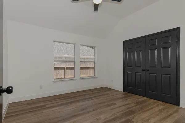 an empty room with wooden floor cabinet and windows