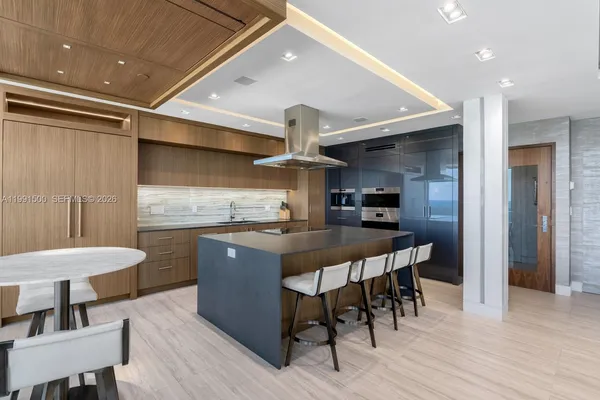 a kitchen with stainless steel appliances a dining table chairs and wooden floor