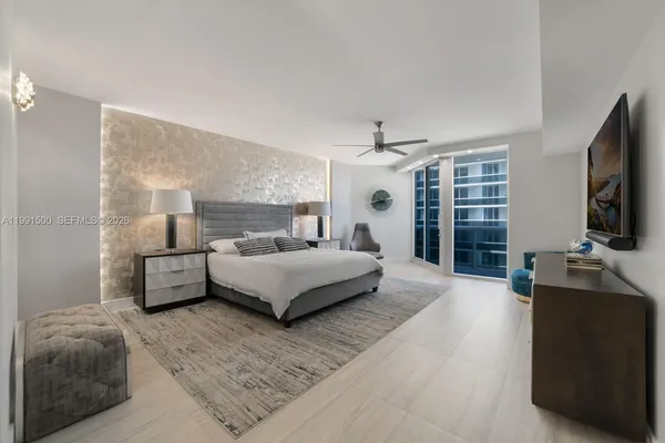 a spacious bedroom with a bed and a flat screen television