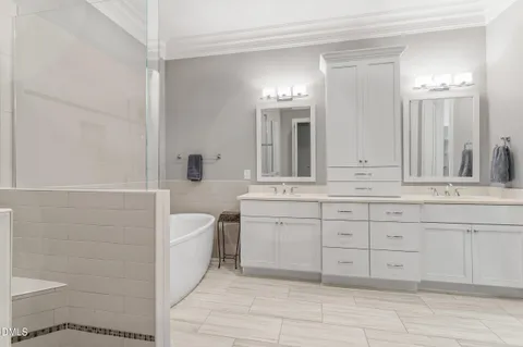 a spacious bathroom with a double vanity sink a mirror a bathtub and