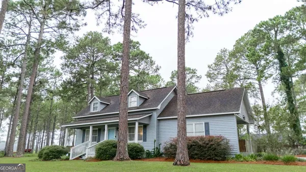 a front view of a house with garden and trees