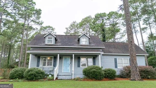 a view of a white house with large windows and a big yard with large trees