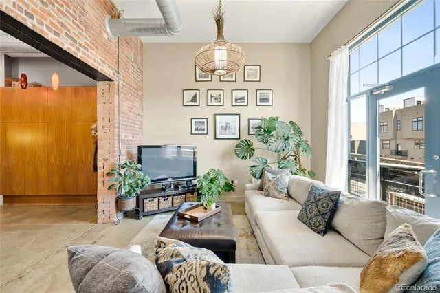 a living room with furniture a chandelier and a floor to ceiling window