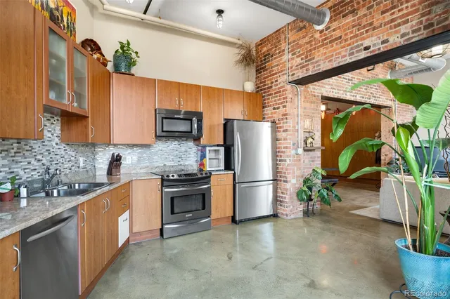 a kitchen with stainless steel appliances granite countertop a refrigerator a sink a stove and dishwasher