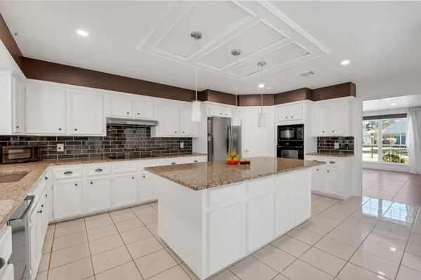 a kitchen with kitchen island granite countertop lots of white stainless steel appliances cabinets and a sink