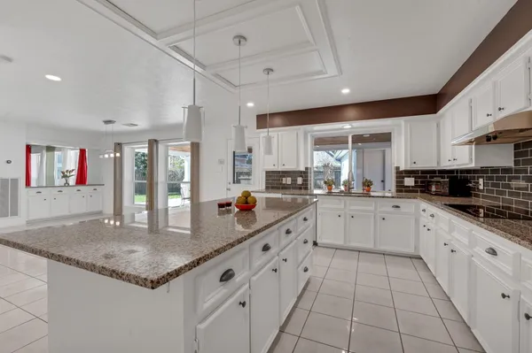 a kitchen with granite countertop a sink and white cabinets