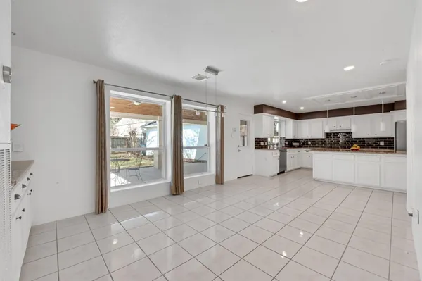 a large white kitchen with white cabinets and refrigerator