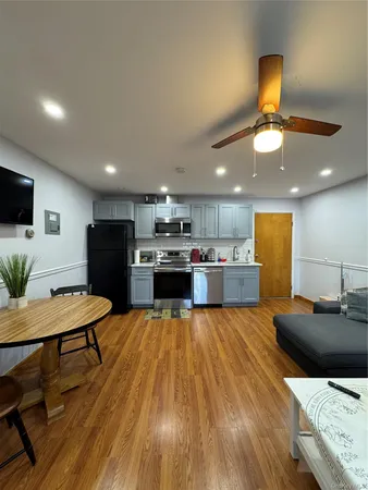 a living room with stainless steel appliances kitchen island granite countertop furniture wooden floor and a view of kitchen
