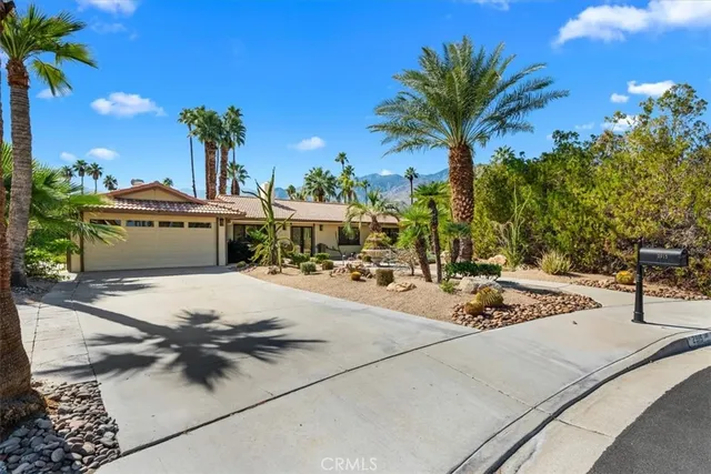 a view of a house with a yard and palm trees