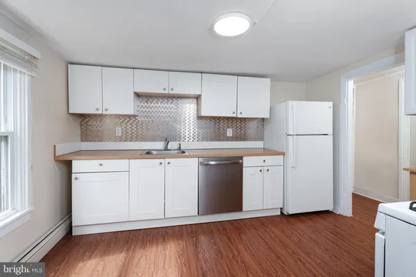 a kitchen with white cabinets white stainless steel appliances and sink