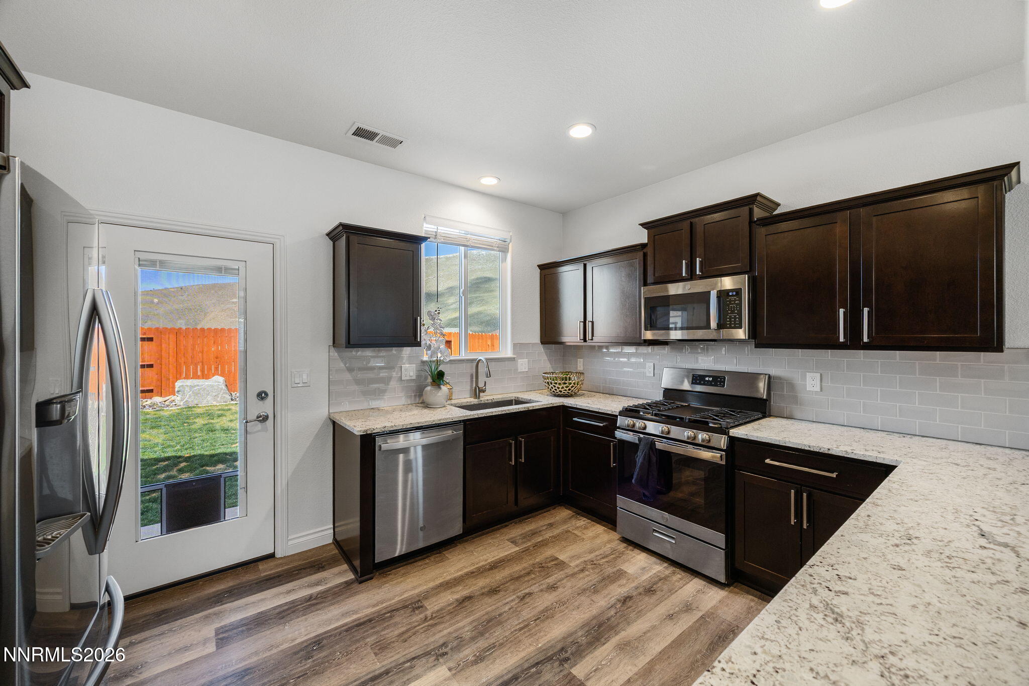 19013 Alpine Walk Reno, NV 89508 - Photo 12 of 34 a kitchen with stainless steel appliances granite countertop a stove a sink dishwasher a refrigerator and a microwave oven with wooden floor