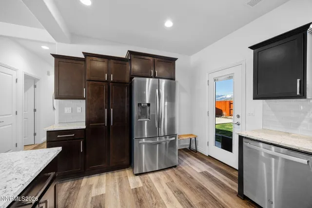 a kitchen with stainless steel appliances granite countertop a refrigerator a stove and a sink with wooden floor