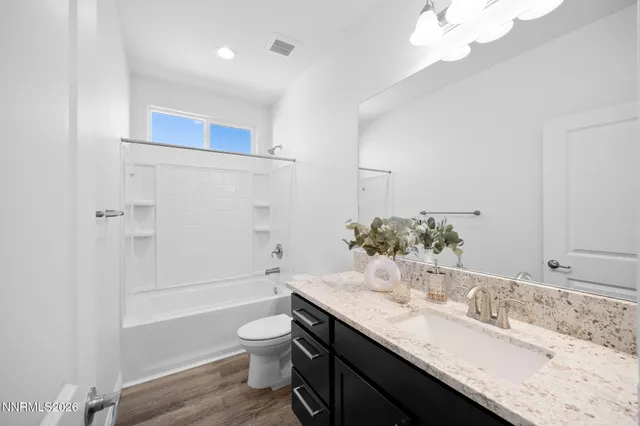 a bathroom with a granite countertop sink toilet a large mirror a bathtub and shower
