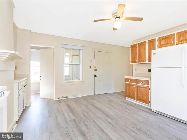 a kitchen with granite countertop a stove a sink and white cabinets with wooden floor next to windows