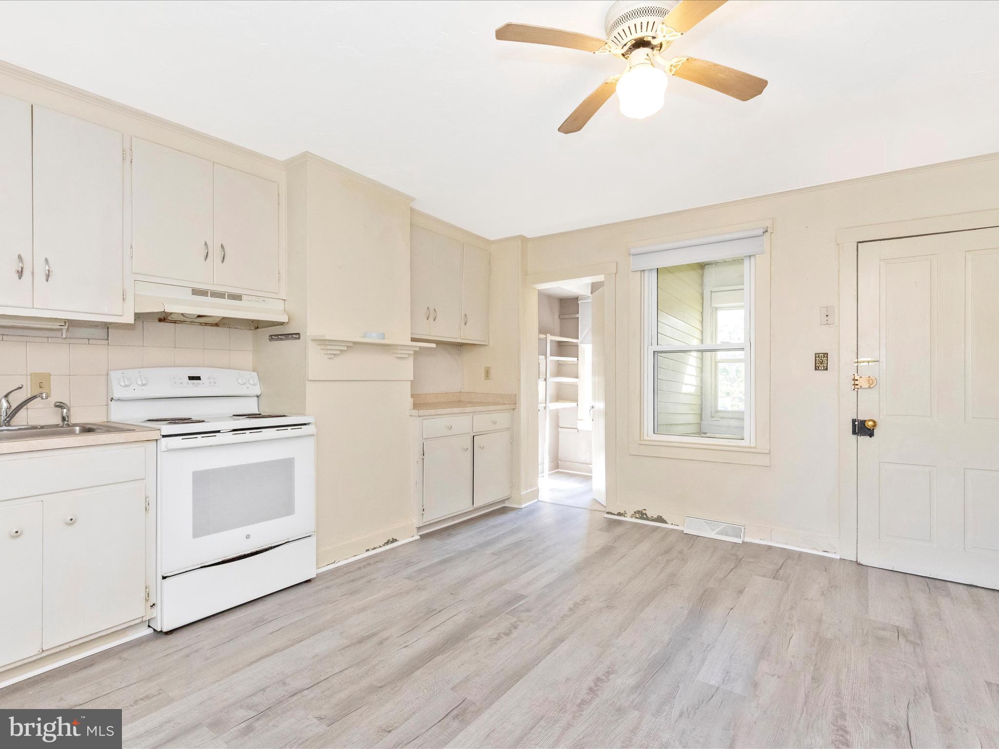 1404 Pleasant Valley Road, Unit 2 Westminster, MD 21158 - Photo 23 of 43 a kitchen with granite countertop a stove a sink and white cabinets with wooden floor next to windows