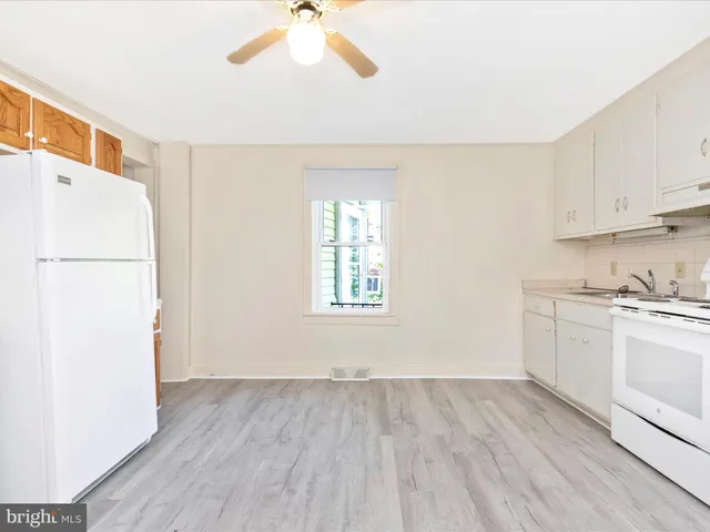 a view of a kitchen with wooden floor and a ceiling fan