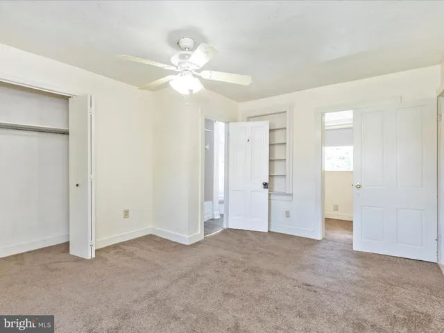 an empty room with a chandelier fan and windows