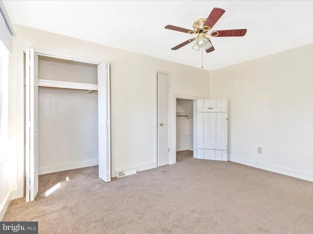 an empty room with windows and fan chandelier