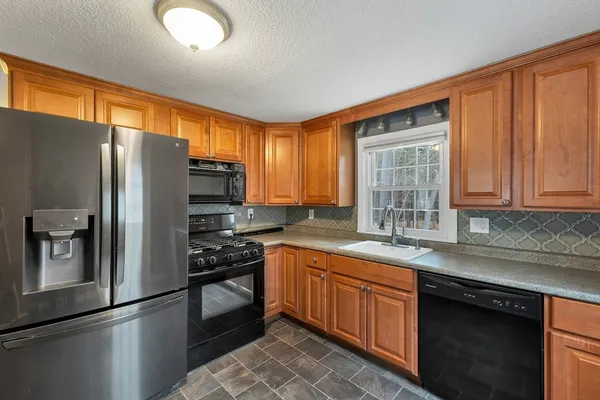 a kitchen with stainless steel appliances granite countertop a refrigerator a sink dishwasher a stove and white cabinets with wooden floor