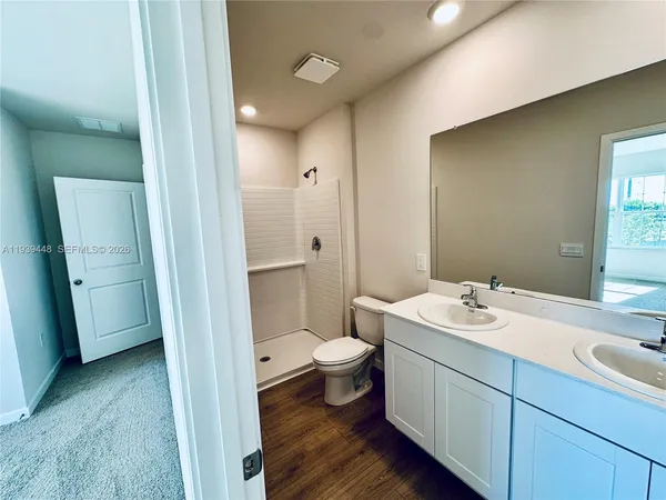 a bathroom with a sink a toilet a shower and a window