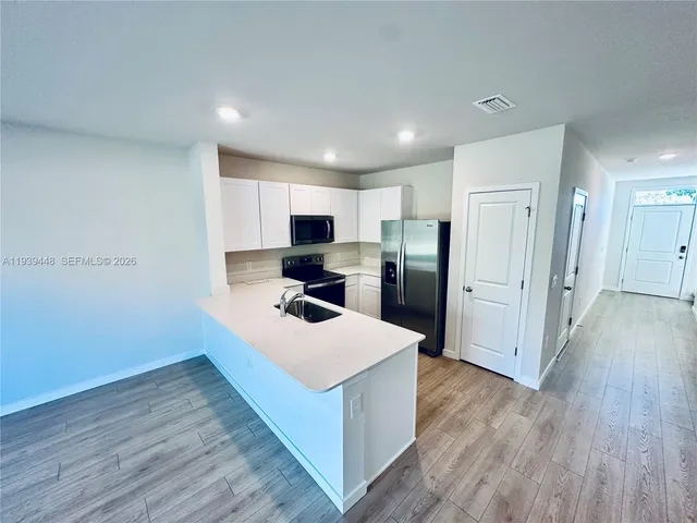 a kitchen with a refrigerator a sink and wooden floor